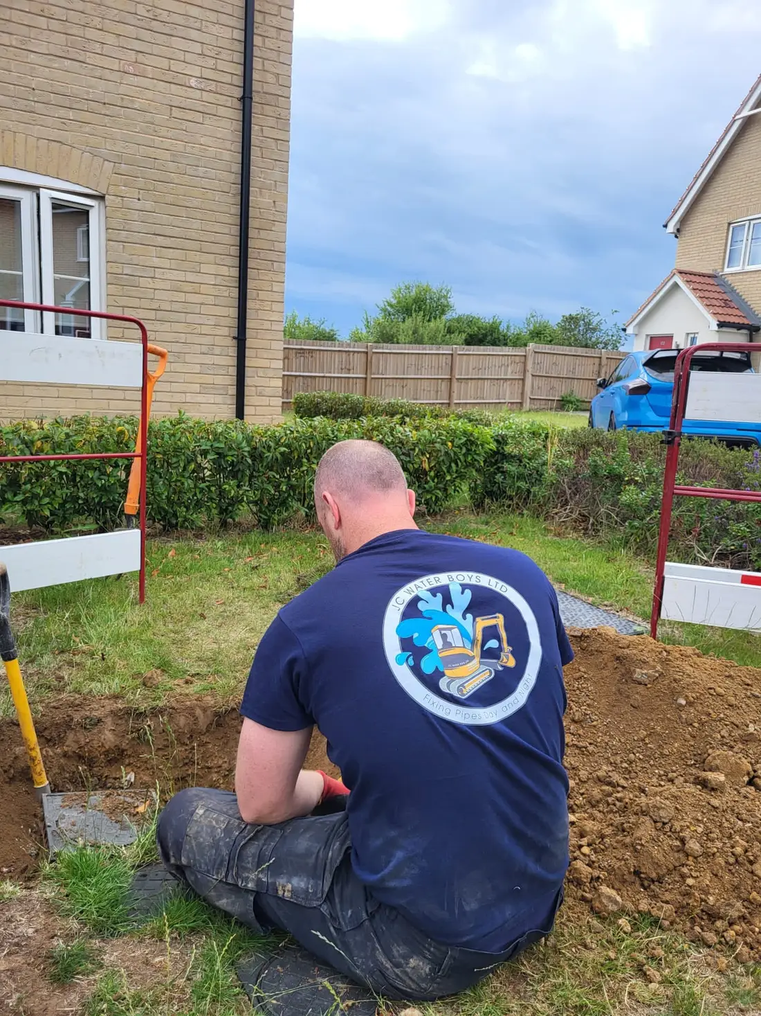 Engineer kneeling beside an excavation in a front garden