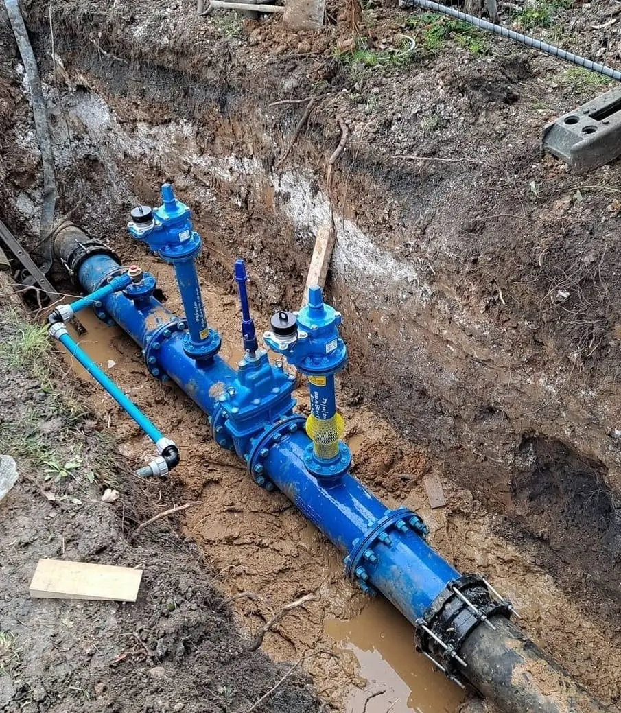 New blue water main with valves and a service connection laid in a trench